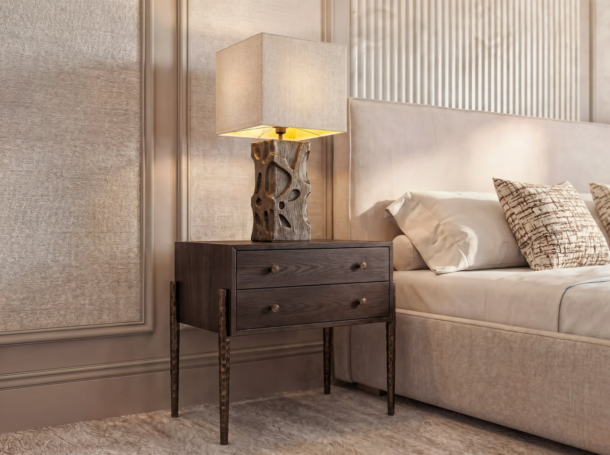 A close-up of a sculptural table lamp on a walnut nightstand